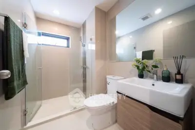 Modern bathroom with sleek design, featuring a glass shower, large mirror, and elegant sink.