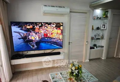 Modern living room with large TV, air conditioning, and stylish decor