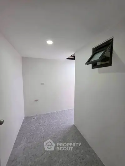 Minimalist interior space with white walls and small window, ideal for storage or utility use.