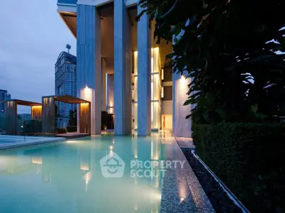 Luxurious modern building with illuminated pool and elegant architecture at dusk.