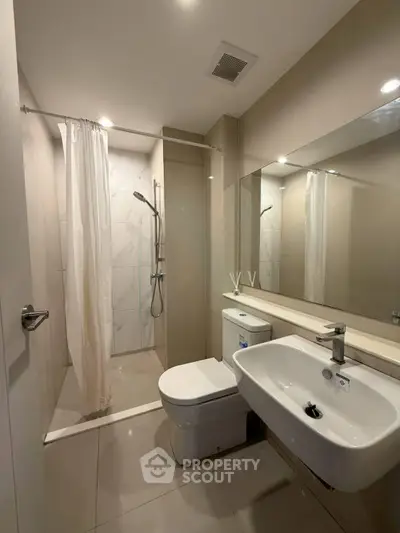 Modern bathroom with sleek fixtures and spacious shower in contemporary apartment.