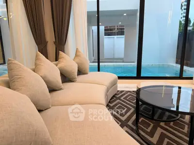 Luxurious living room with pool view, featuring elegant sofa and modern decor.