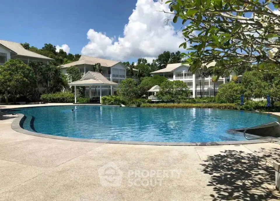 Luxurious resort-style pool with lush greenery and elegant buildings in the background.