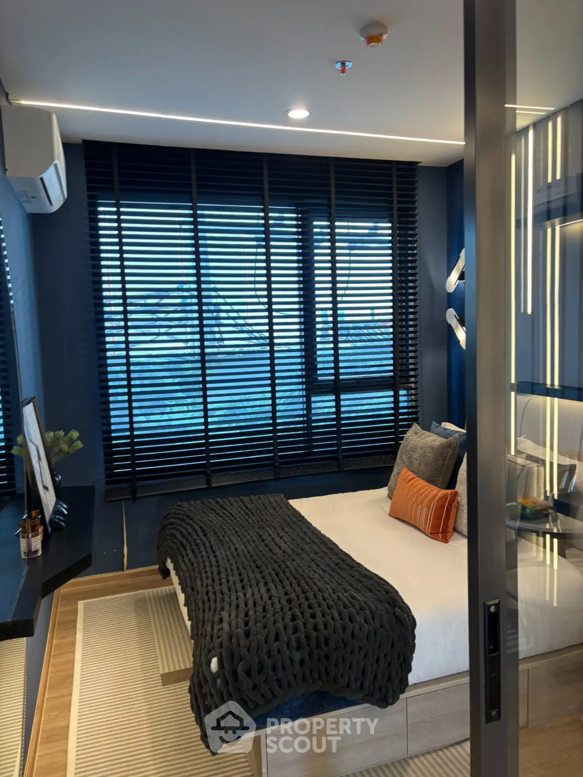 Modern bedroom with stylish decor and large window with blinds, creating a cozy and inviting atmosphere.