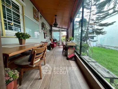 Charming enclosed balcony with wooden ceiling and garden view, perfect for relaxation and entertaining.