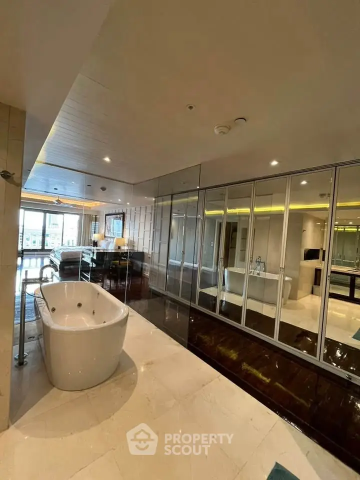 Luxurious bathroom with freestanding bathtub and mirrored walls in modern apartment.