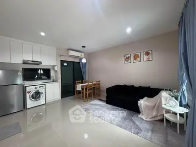 Modern living room with sleek kitchen and cozy dining area, featuring stylish decor and ample natural light.