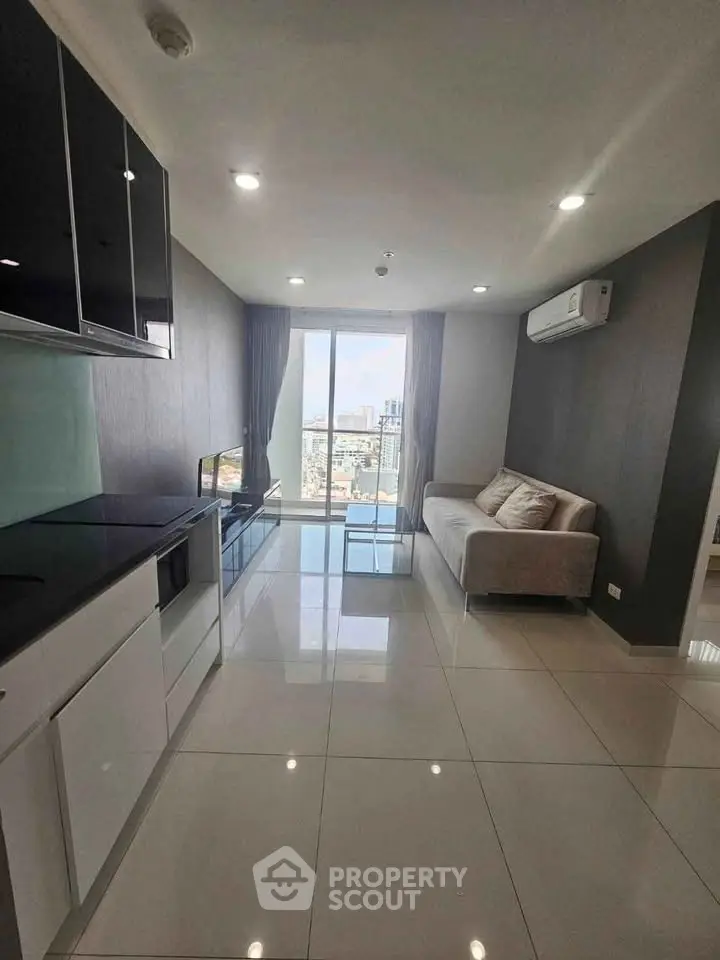 Modern living room with sleek kitchen and city view, featuring stylish furniture and bright lighting.