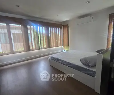Spacious bedroom with large windows and modern air conditioning unit, offering ample natural light and comfort.