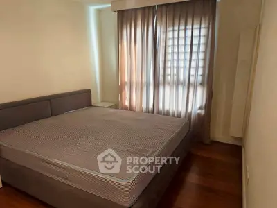 Cozy bedroom with large bed and natural light through window curtains.