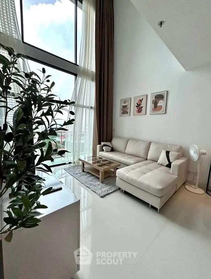 Spacious modern living room with high ceilings and large windows offering stunning city views.