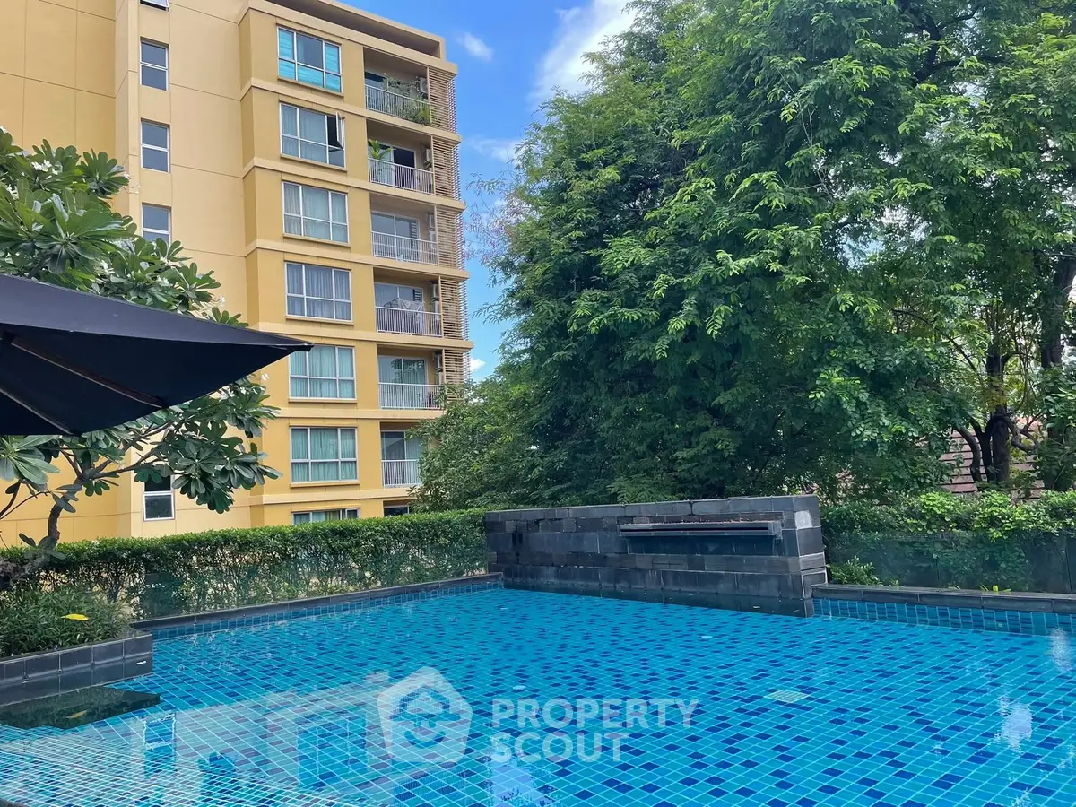 Luxurious apartment building with serene pool and lush greenery