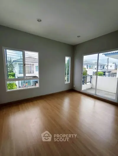 Spacious empty room with large windows and balcony access, offering abundant natural light and modern flooring.