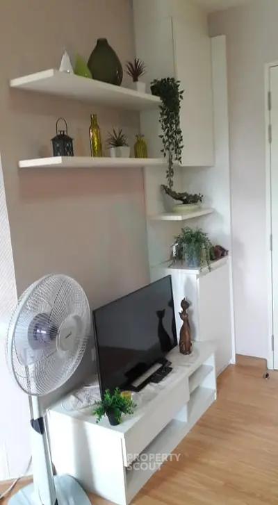 Modern living room with stylish shelving and decor, featuring a sleek TV setup and wooden flooring.