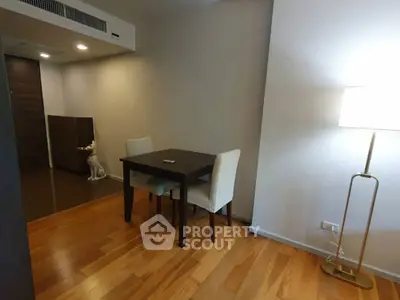 Cozy dining area with wooden flooring and modern lighting in a stylish apartment.