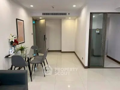Modern apartment interior with dining area and glass table, featuring minimalist decor and bright lighting.