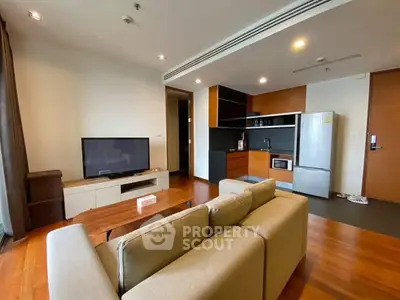 Modern living room with open kitchen, featuring sleek appliances and cozy seating area.
