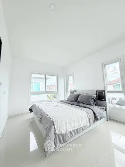 Spacious bedroom with modern design and large windows offering natural light