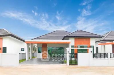 Modern single-story home with striking orange accents and a spacious driveway, set against a clear blue sky, offering a perfect blend of style and comfort.