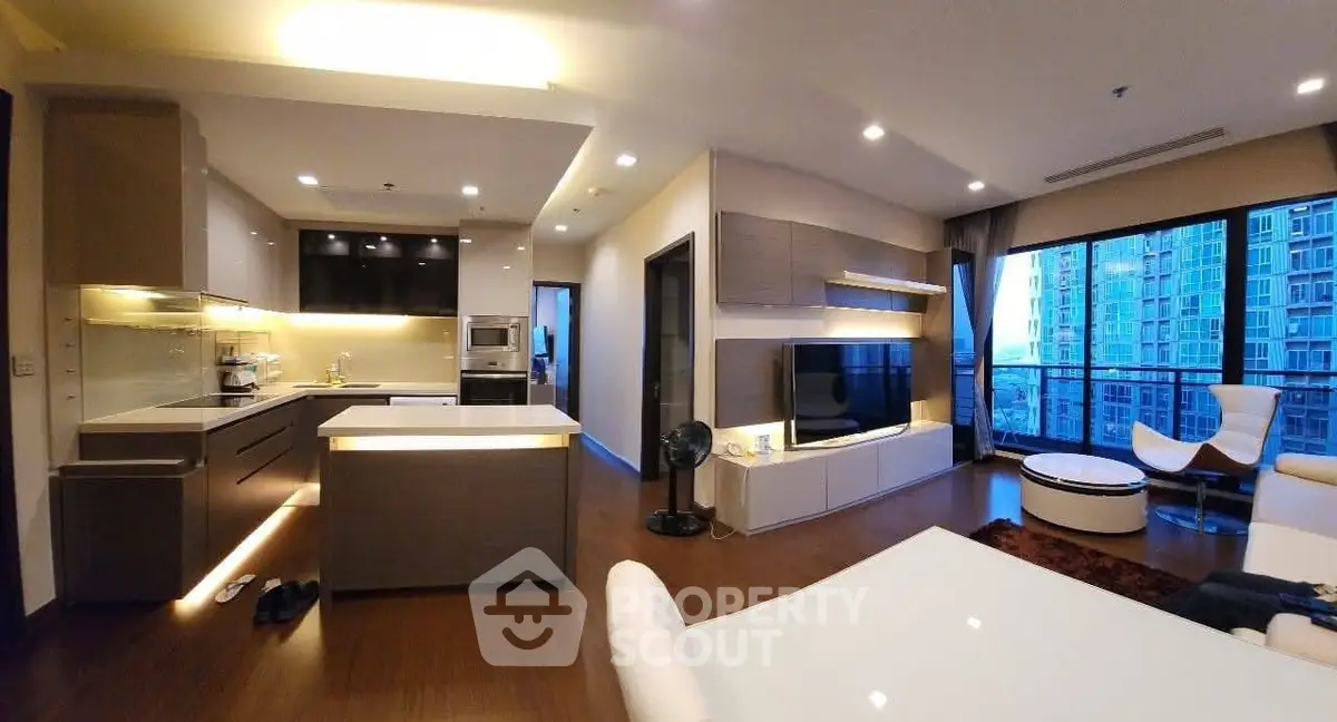 Modern open-plan living room with kitchen, featuring sleek design and large windows with city view.