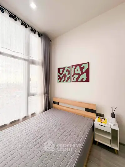 Modern bedroom with large window and stylish decor in a contemporary apartment.