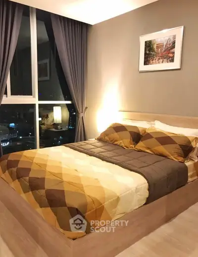 Cozy bedroom with city view, modern decor and large window for natural light.