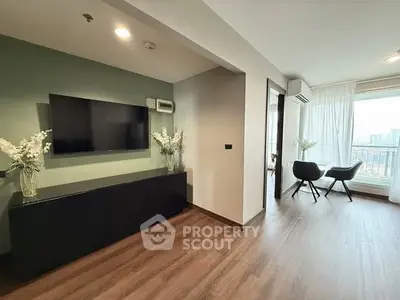 Modern living room with sleek TV setup and city view from balcony.