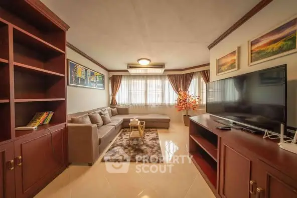 Spacious living room with elegant decor and large TV, perfect for relaxation.