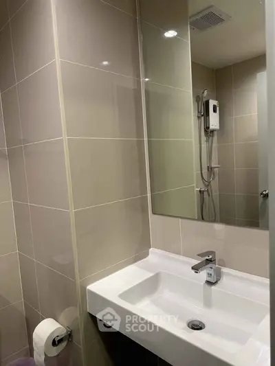 Modern bathroom with sleek sink and shower in contemporary apartment.