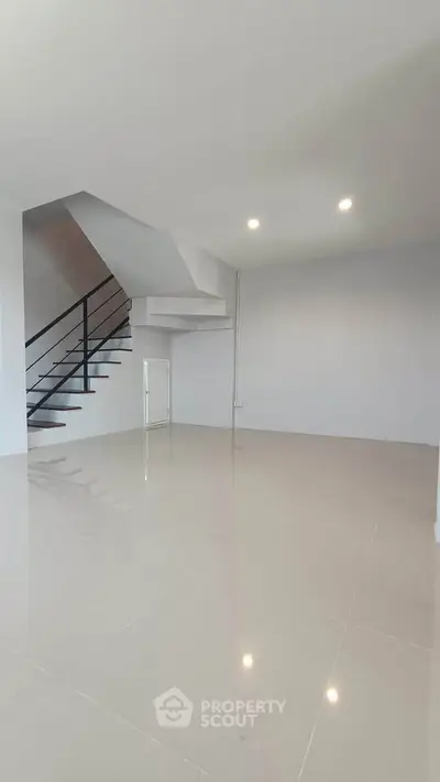 Spacious modern living room with sleek staircase and bright lighting