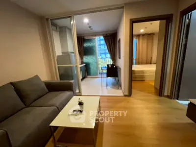 Modern apartment with cozy living room and bedroom, featuring a glass partition and stylish decor.