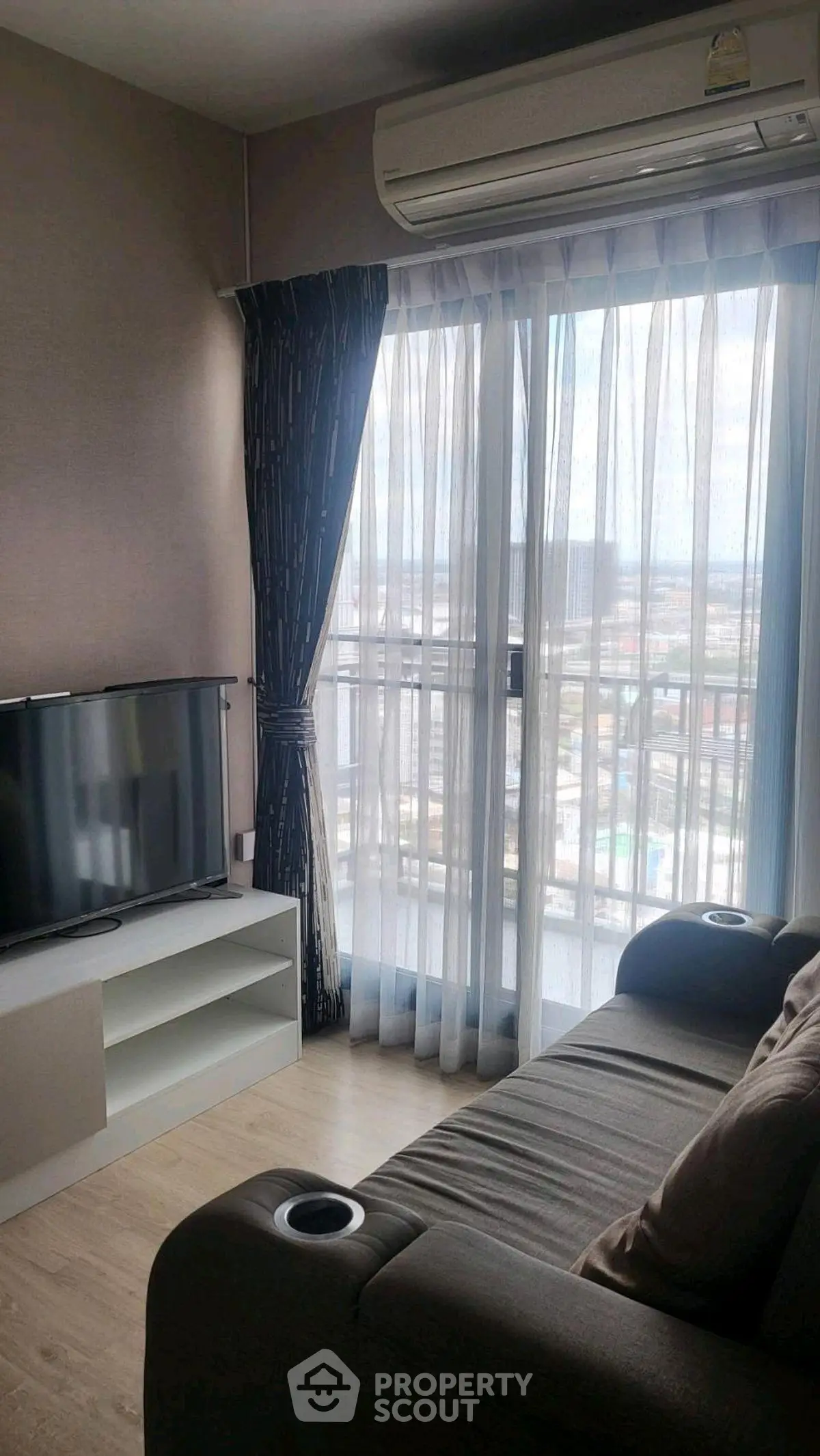 Cozy living room with city view, featuring a comfortable sofa and modern entertainment setup.