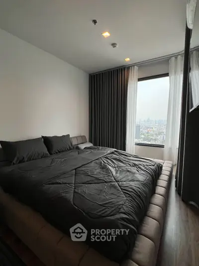 Modern bedroom with city view, featuring a large bed and floor-to-ceiling windows.