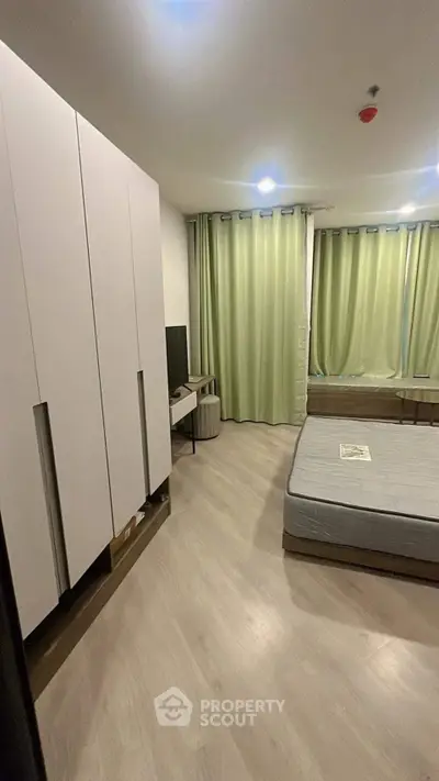 Spacious bedroom with modern furniture and large windows for natural light.