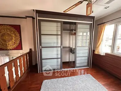 Spacious bedroom with modern sliding wardrobe and wooden flooring