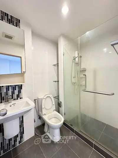 Modern bathroom with glass shower and sleek fixtures in contemporary apartment.