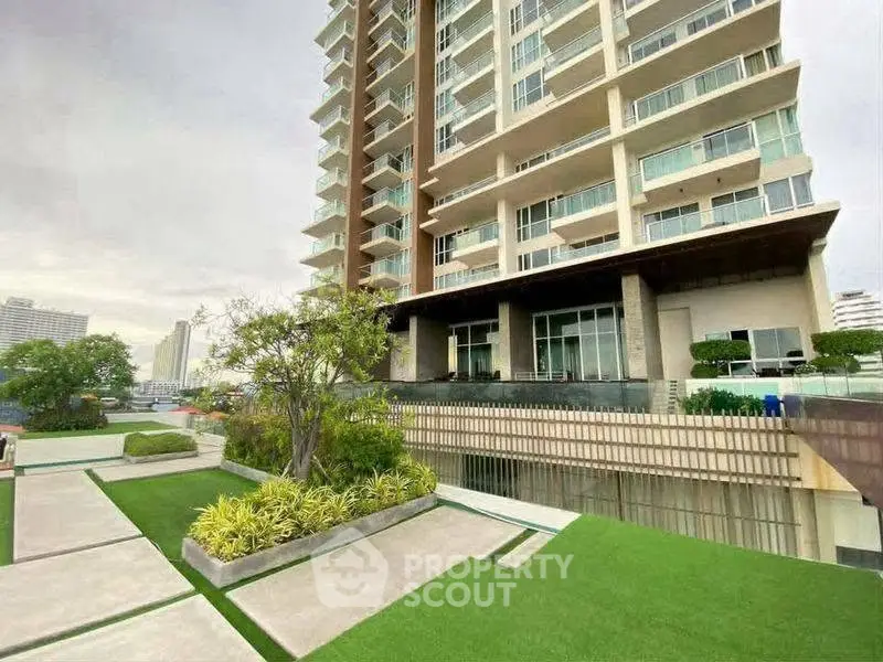 Modern high-rise building with landscaped garden and spacious balconies in urban setting.