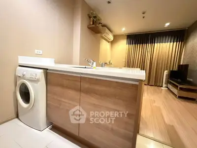 Modern open-layout kitchen with washing machine and stylish living area.