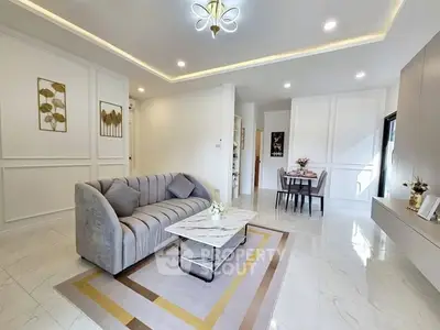 Elegant living room with modern decor and dining area, featuring stylish lighting and marble flooring.