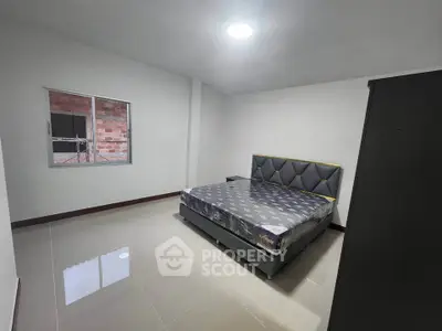 Spacious bedroom with modern bed and large window in minimalist design.
