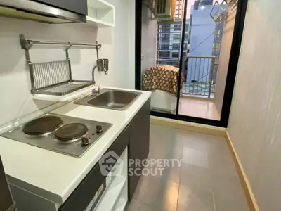 Compact kitchen with electric stove and balcony view in modern apartment