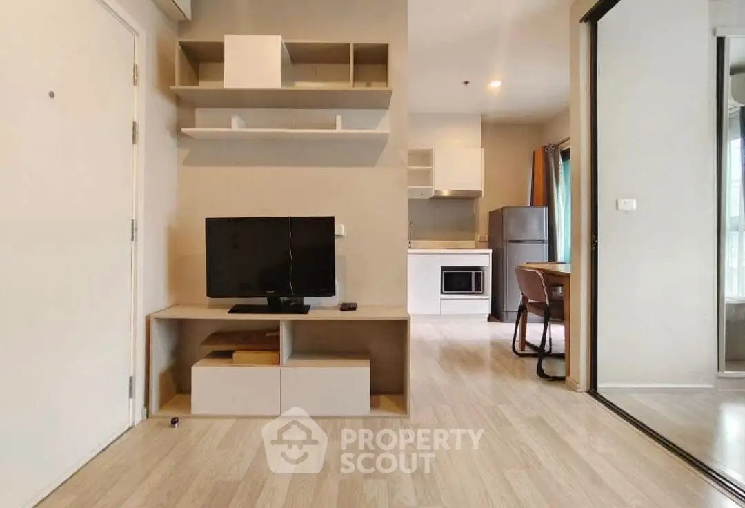 Modern open-plan living room with TV and kitchen area in a stylish apartment.