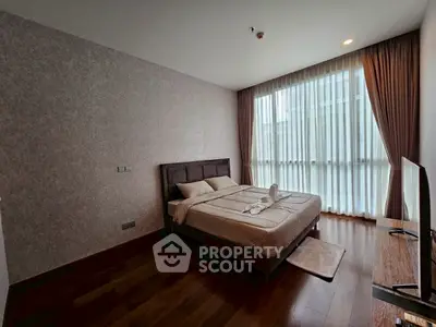 Spacious bedroom with large window and elegant decor in modern apartment.