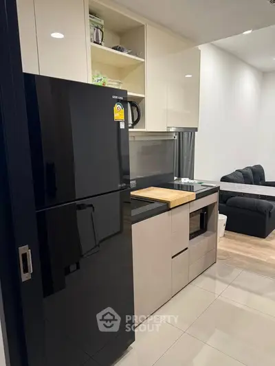 Modern kitchen with sleek black fridge and open shelving in stylish apartment