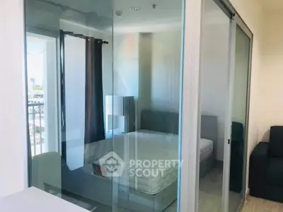 Modern bedroom with glass partition and balcony view in urban apartment.