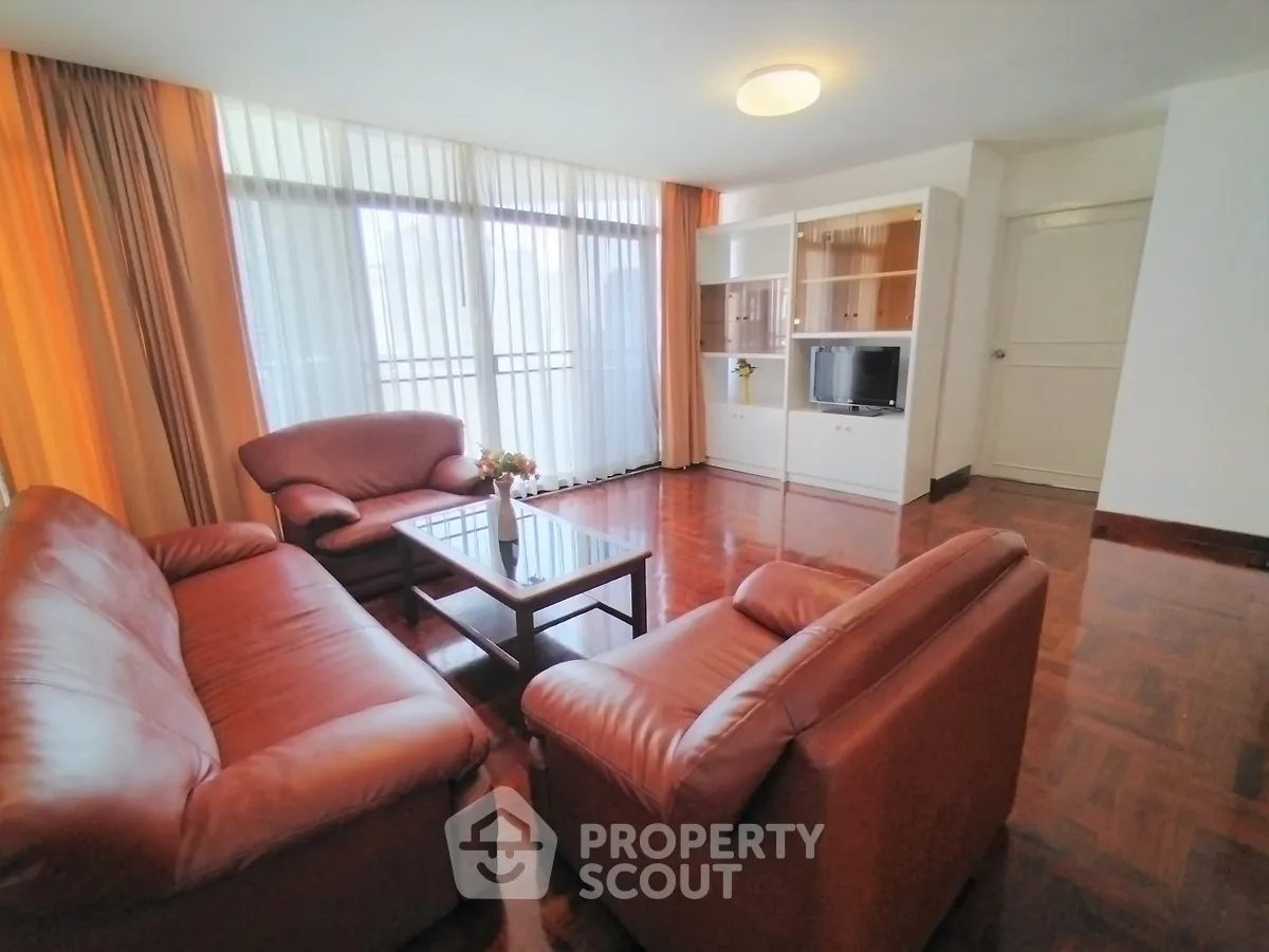 Spacious living room with leather sofas and large windows in a modern apartment.