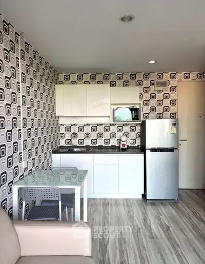 Modern kitchen with stylish wallpaper and sleek appliances in a cozy apartment.