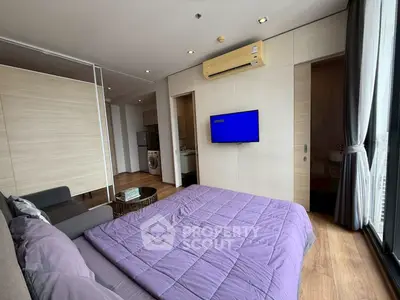 Modern bedroom with TV and washing machine, featuring sleek design and natural light.