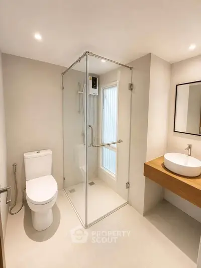 Modern bathroom with glass shower, sleek fixtures, and minimalist design.
