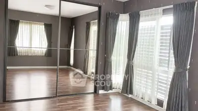Spacious empty room with large mirrored closet and elegant curtains